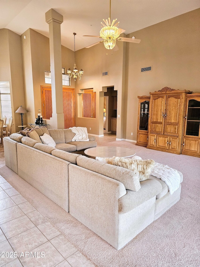 tiled living room featuring high vaulted ceiling and ceiling fan with notable chandelier