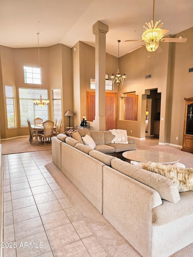 tiled living room with ceiling fan with notable chandelier and a towering ceiling