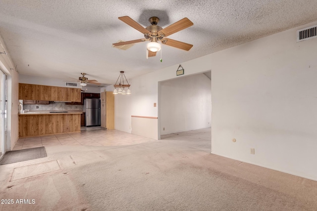 unfurnished living room featuring light carpet, a textured ceiling, and ceiling fan