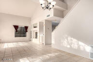 unfurnished living room with tile patterned flooring, high vaulted ceiling, and a notable chandelier