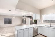 kitchen featuring kitchen peninsula, white cabinetry, and stainless steel dishwasher