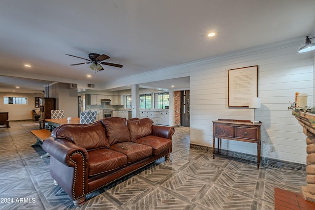 living area with baseboards, a healthy amount of sunlight, and crown molding