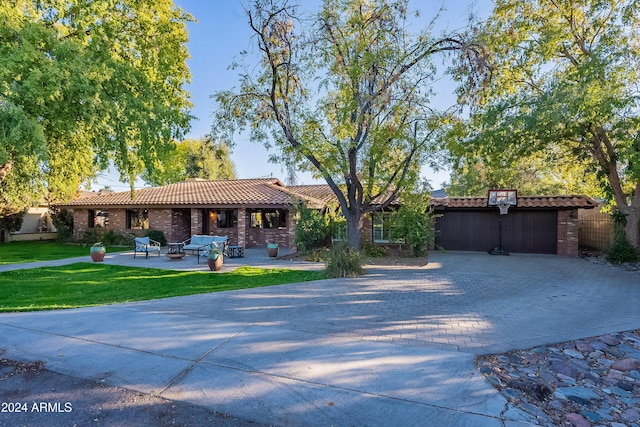 view of front of property featuring brick siding, a front lawn, a tile roof, decorative driveway, and a patio area