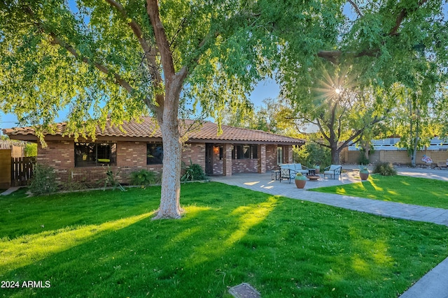 back of property featuring a patio area, a yard, brick siding, and fence