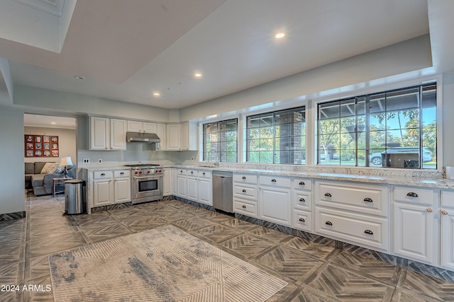 kitchen featuring under cabinet range hood, a sink, white cabinetry, recessed lighting, and stainless steel appliances