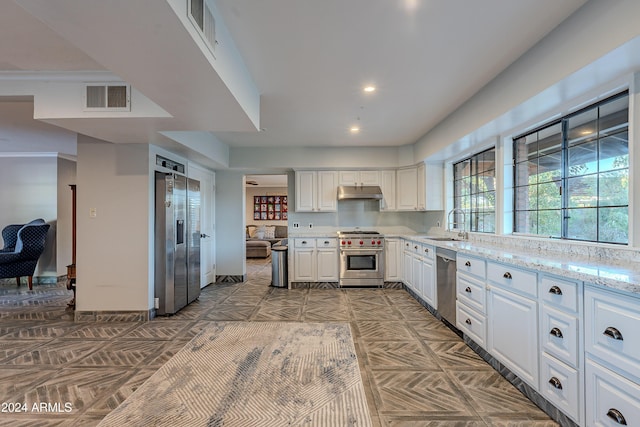 kitchen featuring visible vents, under cabinet range hood, white cabinets, stainless steel appliances, and a sink