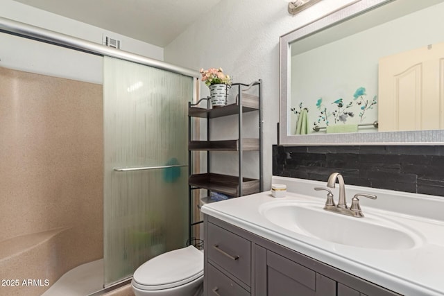 bathroom with vanity, a shower stall, toilet, and visible vents