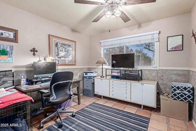 home office featuring light tile patterned floors, tile walls, ceiling fan, and a wainscoted wall