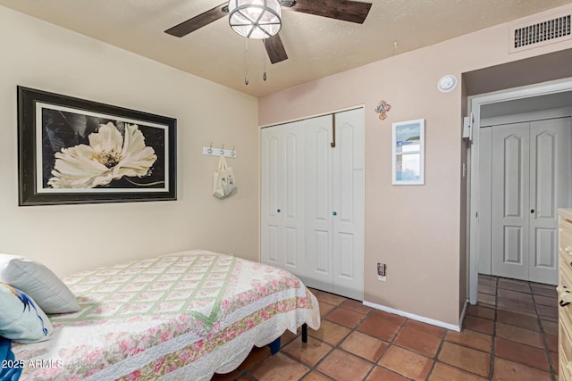 bedroom featuring a ceiling fan, visible vents, tile patterned flooring, baseboards, and a closet