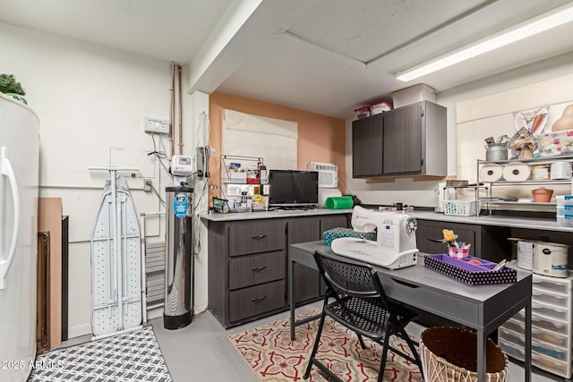 kitchen featuring light countertops, white fridge, concrete flooring, and dark brown cabinets