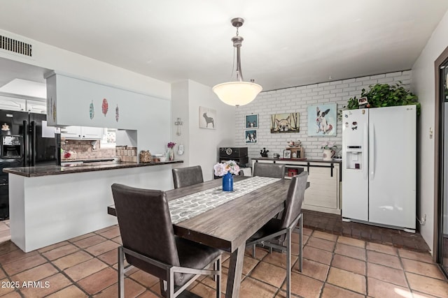dining room featuring visible vents and brick wall