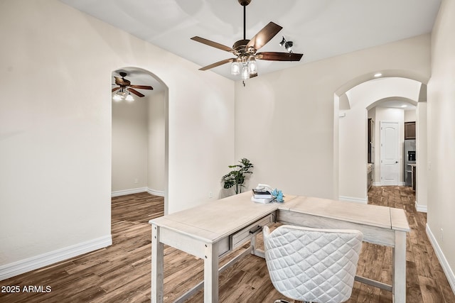 office with arched walkways, baseboards, a ceiling fan, and wood finished floors