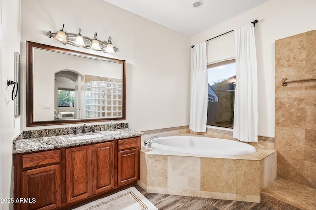 bathroom with vanity, a bath, and wood finished floors
