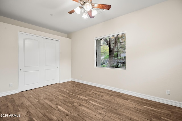 unfurnished bedroom with baseboards, ceiling fan, wood finished floors, and a closet