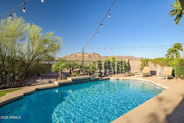 view of pool with fence, a fenced in pool, a mountain view, and a patio area