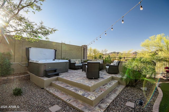 view of patio / terrace with a hot tub, fence, and an outdoor living space