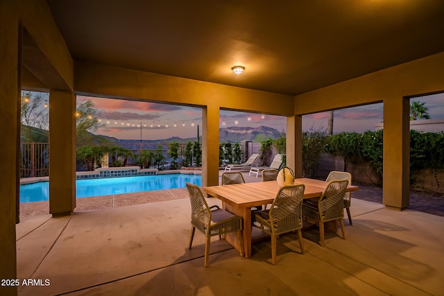 exterior space with fence, a mountain view, an outdoor pool, and outdoor dining space