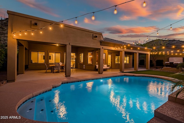 pool at dusk featuring an outdoor pool and a patio area