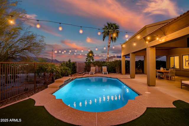 pool at dusk featuring a patio, a fenced in pool, and a fenced backyard