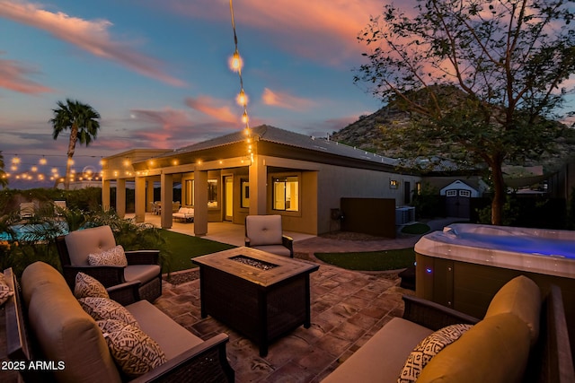 exterior space featuring an outdoor living space with a fire pit, a storage unit, a hot tub, central air condition unit, and an outbuilding