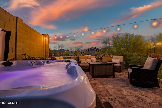 patio terrace at dusk with outdoor lounge area and a hot tub