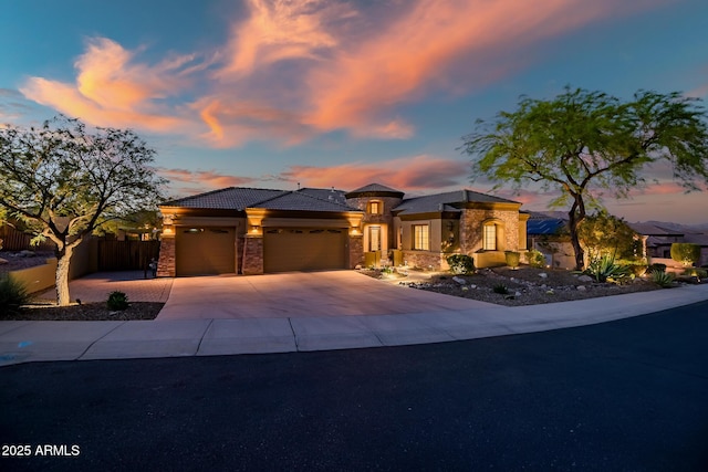 prairie-style house with driveway, a garage, fence, stone siding, and stucco siding