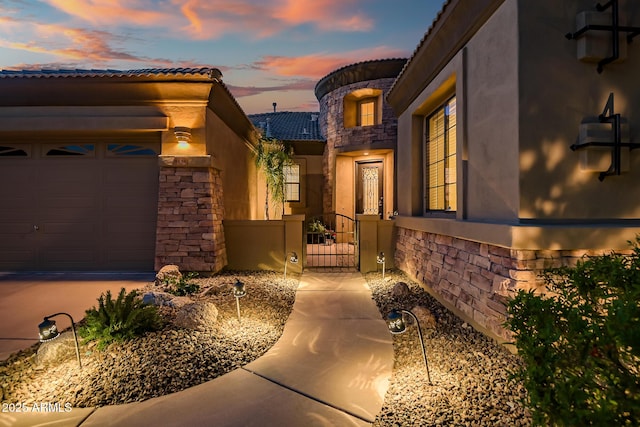 doorway to property with a gate, stucco siding, a tile roof, and stone siding