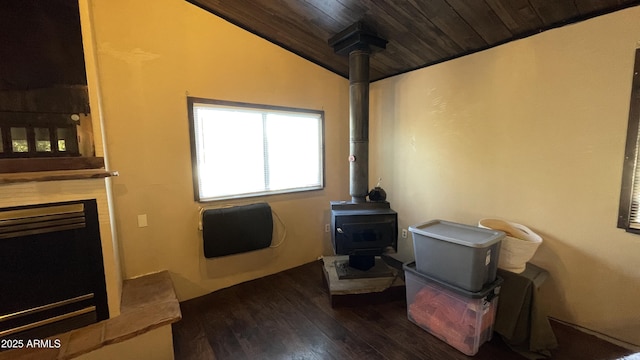 interior space featuring vaulted ceiling, dark hardwood / wood-style floors, a fireplace, a wood stove, and wooden ceiling