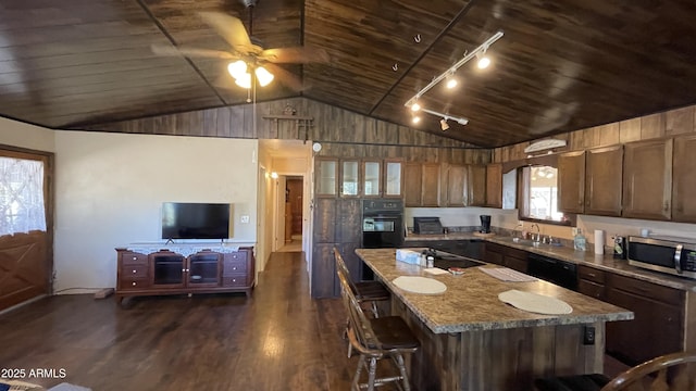 kitchen featuring a kitchen island, sink, black appliances, light stone countertops, and dark wood-type flooring