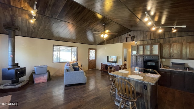 interior space featuring wood walls, wood ceiling, a wood stove, dark hardwood / wood-style flooring, and ceiling fan