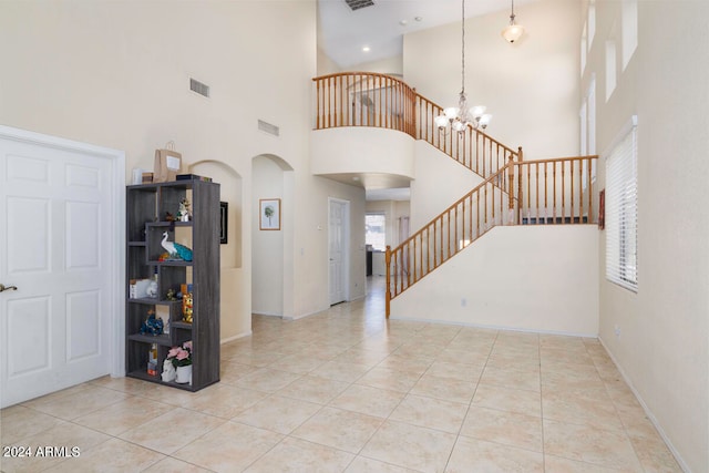 tiled entrance foyer with a towering ceiling and a chandelier