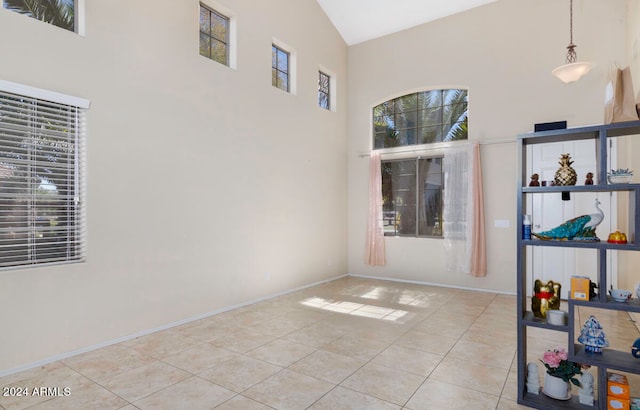 empty room featuring high vaulted ceiling and light tile flooring