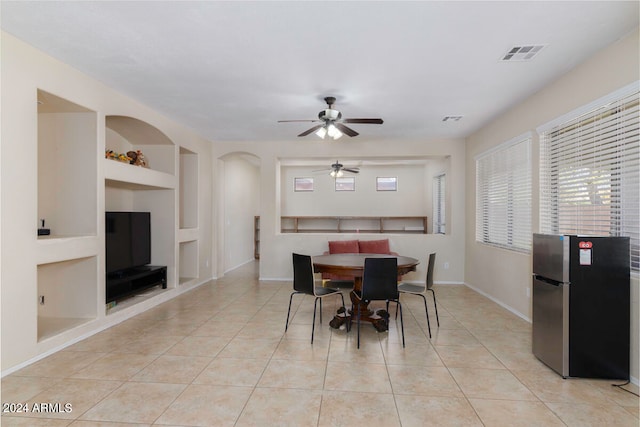 tiled dining area with ceiling fan and built in shelves