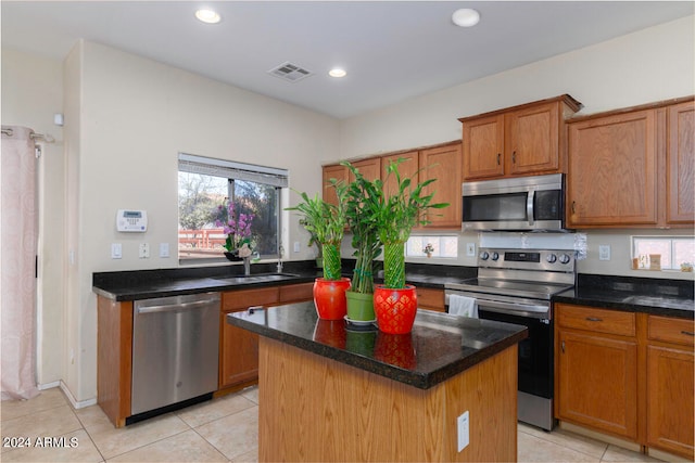 kitchen with a center island, sink, light tile floors, and stainless steel appliances