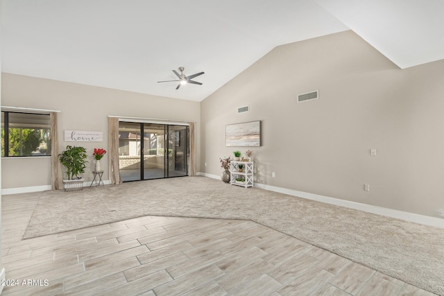 unfurnished living room with light colored carpet, ceiling fan, and high vaulted ceiling