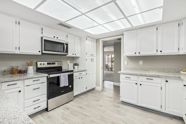 kitchen featuring white cabinets, stainless steel appliances, and light stone countertops