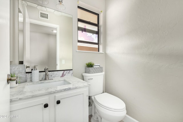 bathroom featuring vanity with extensive cabinet space and toilet