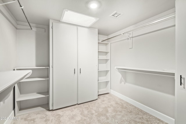 walk in closet with light colored carpet