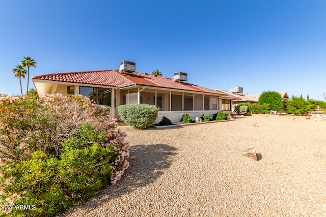 rear view of house featuring central air condition unit and a sunroom