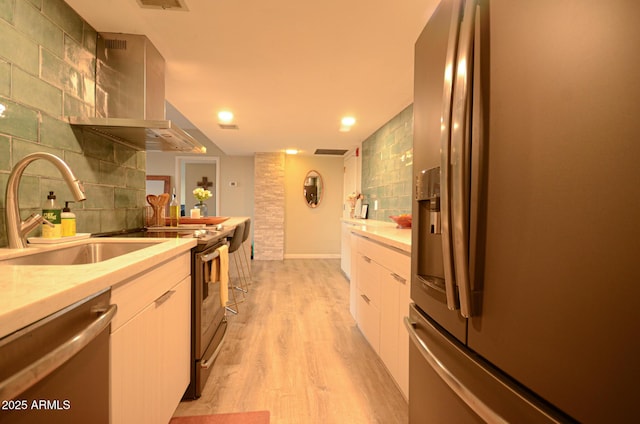 kitchen featuring tasteful backsplash, appliances with stainless steel finishes, sink, and light hardwood / wood-style flooring