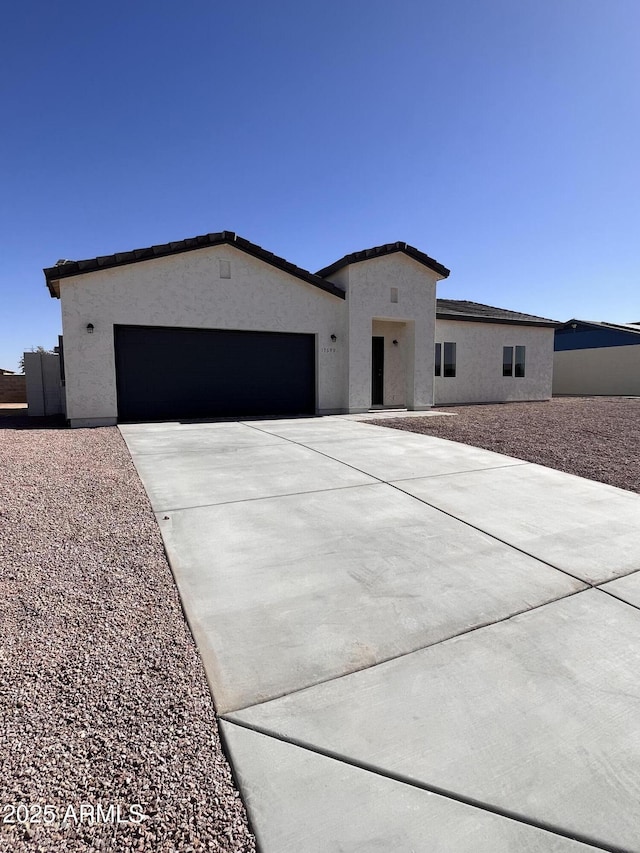 view of front facade featuring an attached garage, concrete driveway, and stucco siding