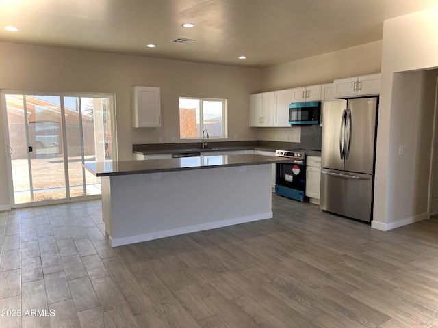 kitchen with appliances with stainless steel finishes, wood finished floors, visible vents, and white cabinetry