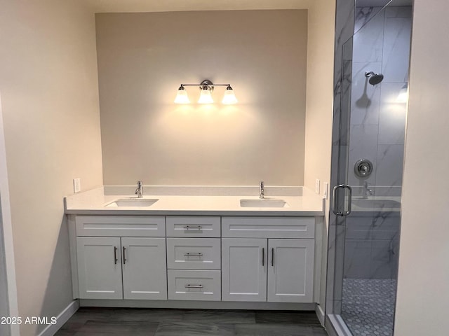 full bath with double vanity, a stall shower, a sink, and baseboards