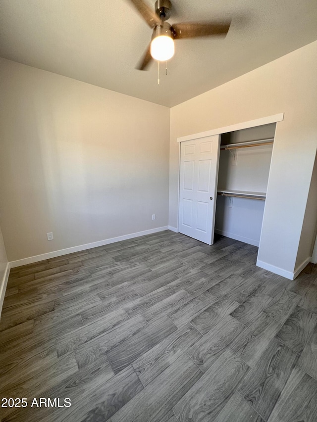 unfurnished bedroom with dark wood-style floors, a closet, baseboards, and a ceiling fan