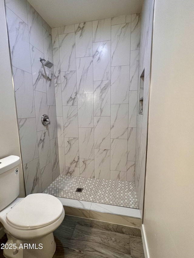 bathroom featuring a tile shower and toilet