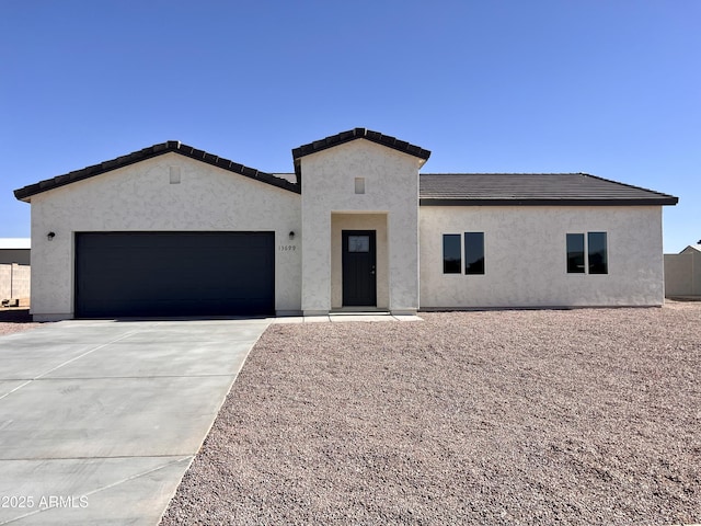 view of front facade with a tile roof, driveway, an attached garage, and stucco siding