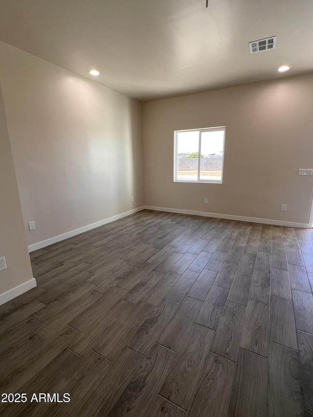 empty room featuring dark wood-style flooring, recessed lighting, visible vents, and baseboards