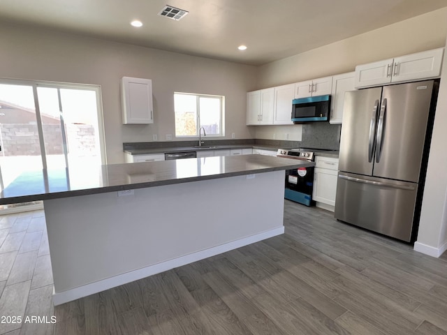 kitchen featuring stainless steel appliances, a sink, visible vents, and white cabinetry