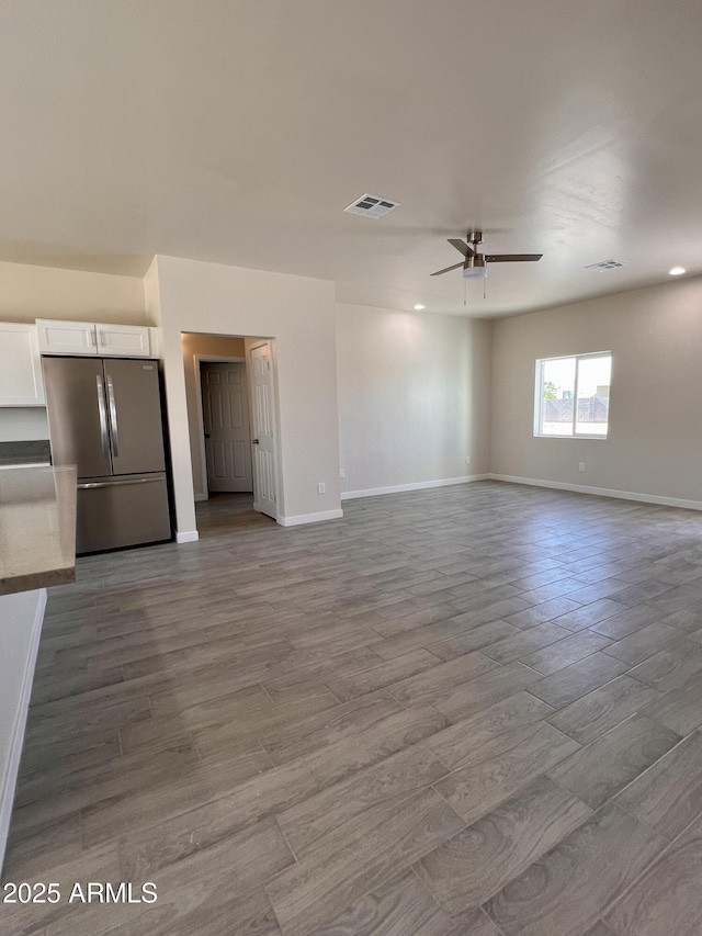 unfurnished living room featuring baseboards, visible vents, and wood finished floors