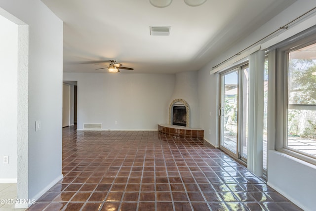 unfurnished living room with visible vents, a wealth of natural light, and a large fireplace